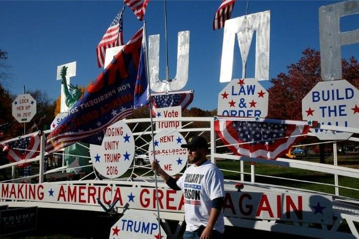 A man poses in front of a Trump sign as he waits to see US Republican Presidential nominee Donald Trump address supporters on November 6, 2016 in Sterling Heights, Michigan