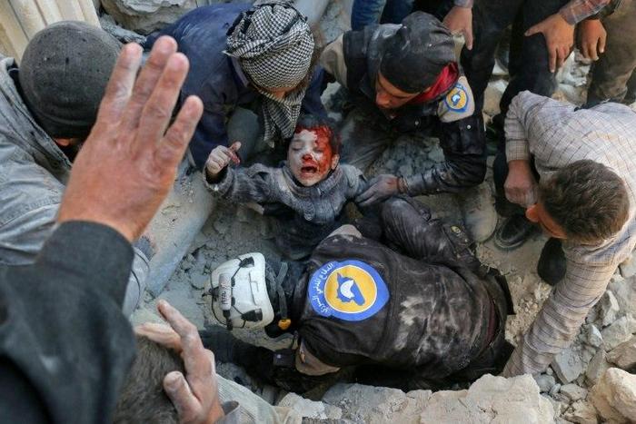 Syrian civil defence volunteers, known as the White Helmets, rescue a boy from the rubble following an attack on the Bab al-Nairab neighbourhood of Aleppo on November 24, 2016