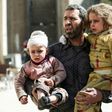 A Syrian man carries two injured children after a reported air strike in the rebel-controlled town of Hammuriyeh, on the outskirts of the capital Damascus, on March 25, 2017