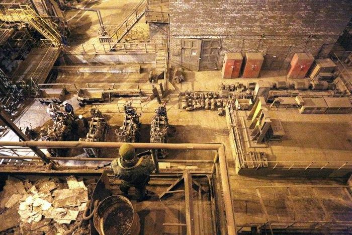 Pro-Russian rebel guards as workers work at the Uzov Metallurgical Works in Donetsk on March 1, 2017