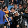 A security staff holds Lyon's goalkeeper Anthony Lopes (C) during scuffles at half-time between some of Lyon's players and Bastia supporters who invaded the pitch on April 16, 2017 in Bastia on the French Mediterranean island of Corsica
