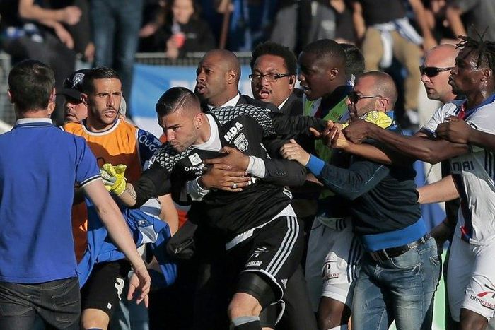 A security staff holds Lyon's goalkeeper Anthony Lopes (C) during scuffles at half-time between some of Lyon's players and Bastia supporters who invaded the pitch on April 16, 2017 in Bastia on the French Mediterranean island of Corsica