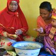 Toddler Salsa Djafar sits on her mother's lap during a circumcision ceremony in Gorontalo, Indonesia, led by a traditional healer