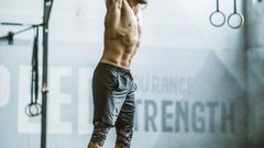 Full length of male athlete exercising strength with barbell in a health club.