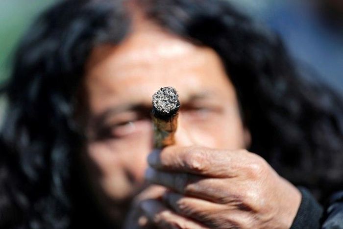 An Israeli smokes a marijuana joint in Jerusalem on April 20, 2017 during a rally to express their defiance of current laws