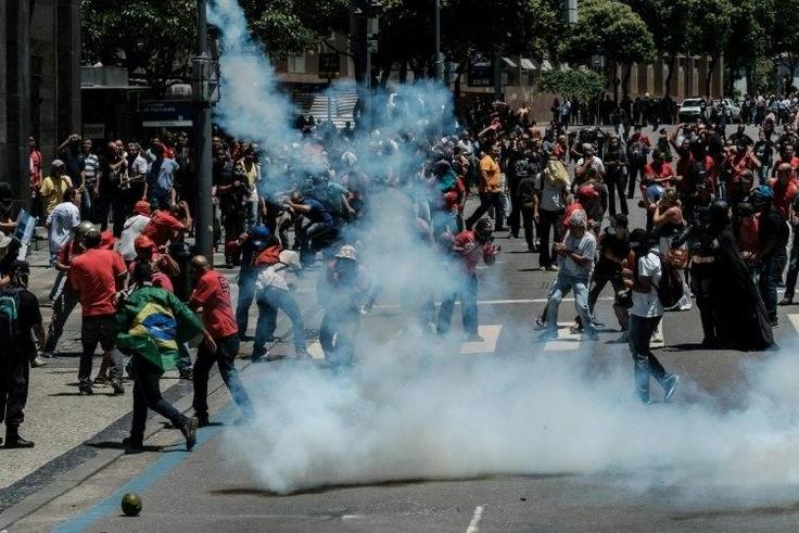 Protesters run away from tear gas during clashes with riot police following a public servants protest against austerity measures in front of the Rio de Janeiro state assembly on December 6, 2016