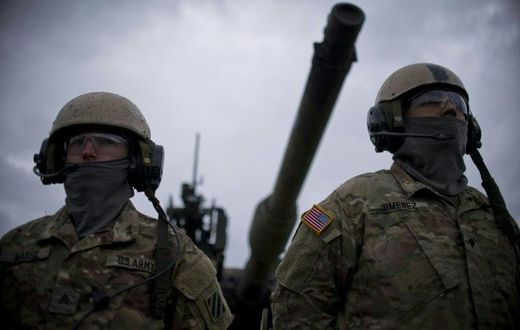 US army soldiers stand in front of an Abrams tank during a joint military tactical training exercise with Bulgaria's army at Novo Selo military ground in Bulagaria on April 11, 2016