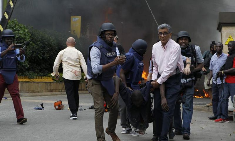 Journalists and foreign security officials help a survivor (Twitter)