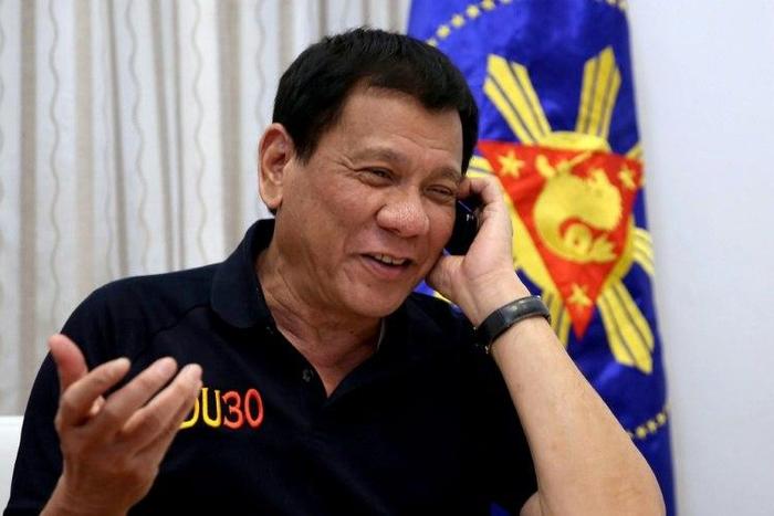 Philippines' President Rodrigo Duterte talks to US President-elect Donald Trump on the phone at Legaspi Suites in Davao City