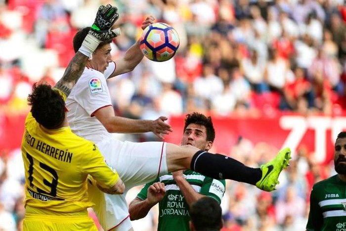 Sevilla's Clement Lenglet (C) jumps for the ball with Leganes' Iago Herrerin during their match in Sevilla on March 11, 2017