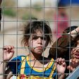 Iraqi children displaced from the battleground city of Mosul stand behind a fence at a camp in the village of Hasan Sham, 30 kilometres (18 miles) away