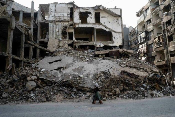 Syrian girls walk past destroyed buildings in the rebel-held town of Douma on the eastern outskirts of Damascus on May 6, 2017