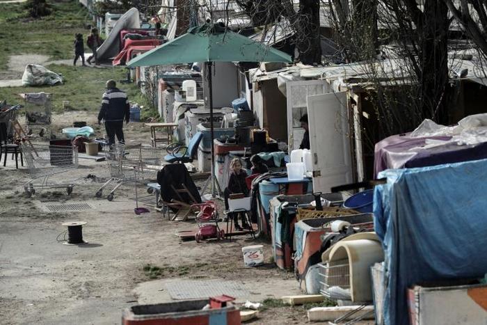 Members of the Roma community stand in a camp that was attacked during the night of March 25 in Bobigny, near Paris