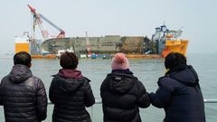 Relatives of the missing from the Sewol ferry disaster look at the damaged ferry during a memorial service from a ship off the coast of the southern South Korean island of Jindo on March 28, 2017