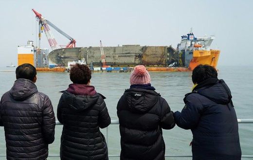 Relatives of the missing from the Sewol ferry disaster look at the damaged ferry during a memorial service from a ship off the coast of the southern South Korean island of Jindo on March 28, 2017