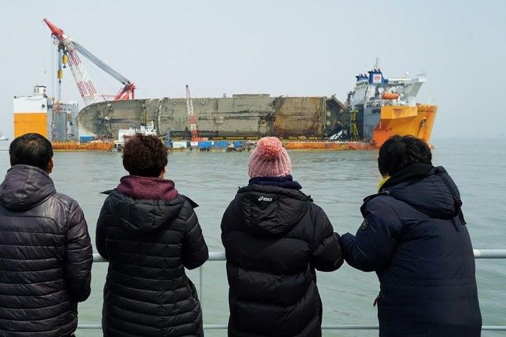 Relatives of the missing from the Sewol ferry disaster look at the damaged ferry during a memorial service from a ship off the coast of the southern South Korean island of Jindo on March 28, 2017