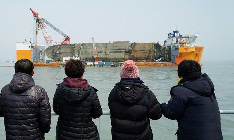 Relatives of the missing from the Sewol ferry disaster look at the damaged ferry during a memorial service from a ship off the coast of the southern South Korean island of Jindo on March 28, 2017