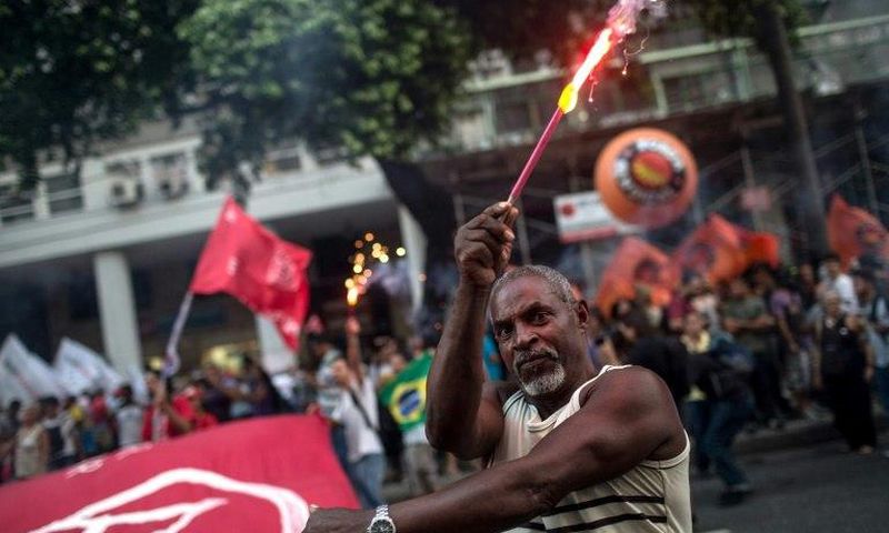 A protester holds fireworks during a demonstration against the Brazilian government's social welfare reform bill in Rio de Janeiro, on March 15, 2017
