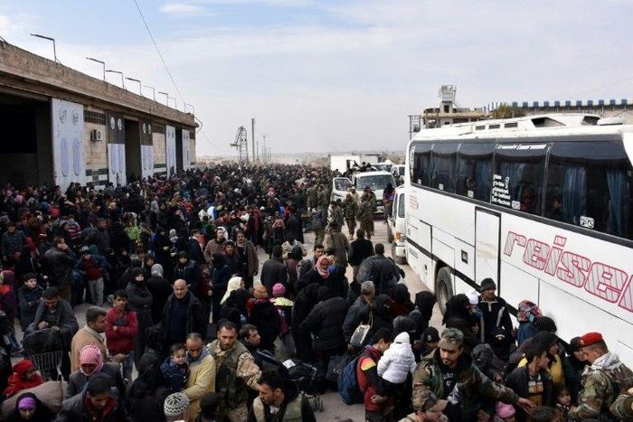 Syrian families, fleeing from various eastern districts of Aleppo, queue to get onto buses on November 29, 2016