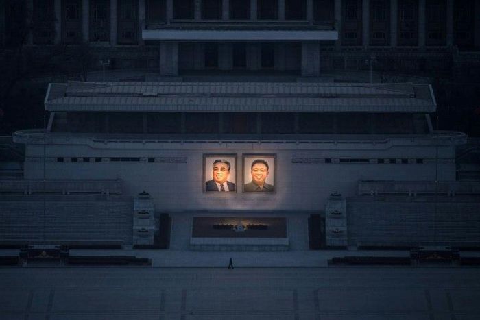 A pedestrian passes portraits of late North Korean leaders Kim Il-Sung (L) and Kim Jong-Il in Pyongyang, seen from the landmark Juche tower on February 17, 2017