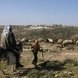 A Palestinian man and a child are seen in the village of Sair near the Israeli settlement of Metzad