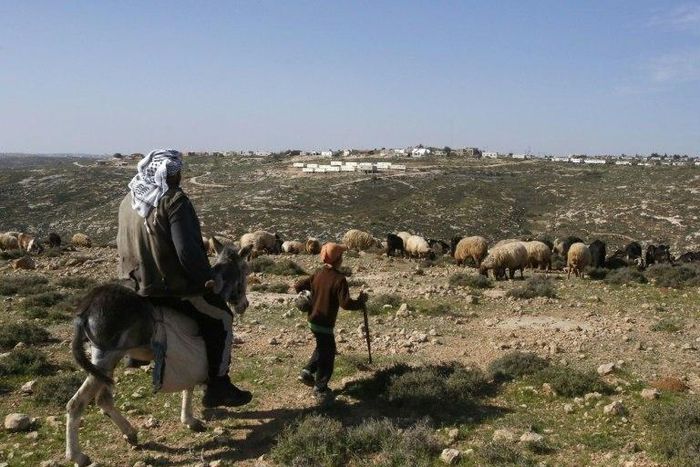 A Palestinian man and a child are seen in the village of Sair near the Israeli settlement of Metzad