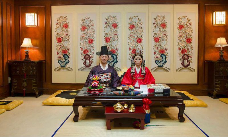 A korean couple pose for pictures at their wedding ceremony