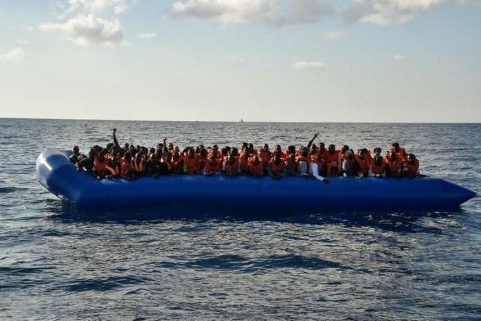 Migrants and refugees seated on a rubber boat wait to be evacuated during a rescue operation on November 4, 2016 off the Libyan coast