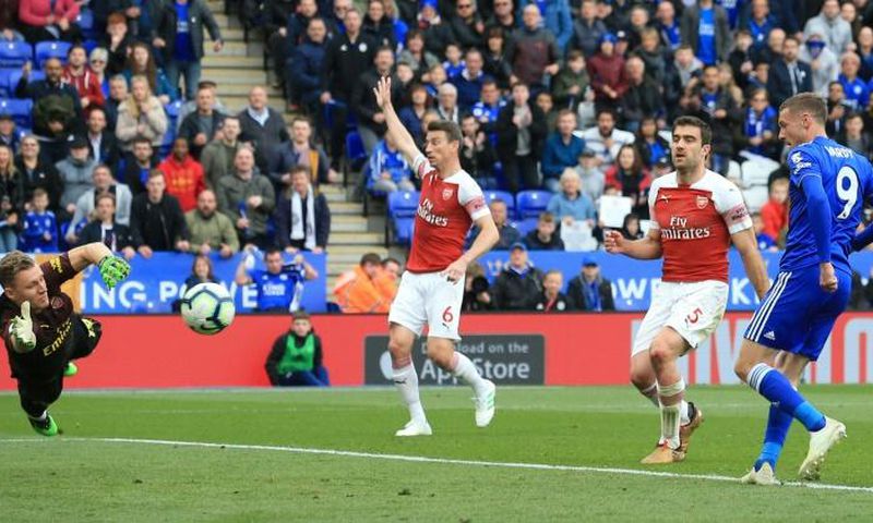Jamie Vardy (R) slots the ball past Arsenal goalkeeper Bernd Leno (L) to complete a 3-0 win for Leicester