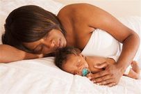 Woman sleeping with baby(Masterfile)
