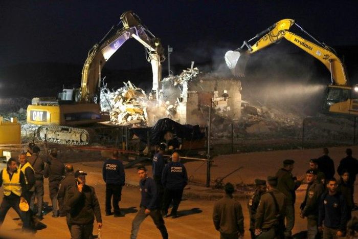 Diggers under the supervision of Israeli forces destroy a house in the Jewish settlement of Ofra in the occupied West Bank, on February 28, 2017