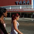 Cubans walk past a movie theater announcing the Havana Latin American Film Festival