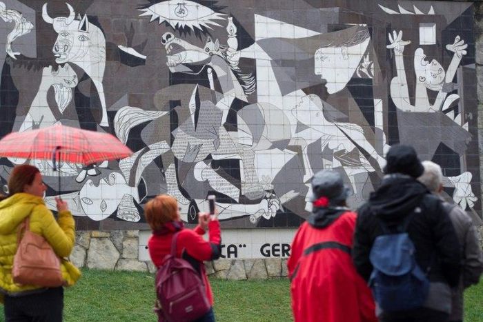 Tourists take pictures of a mural depicting Pablo Picasso's painting "Guernica" in the northern Spanish town on the 80th aniversary of a Nazi bombing raid that killed hundreds