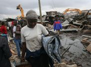 Members of the public watch as a bulldozer demolishes a building