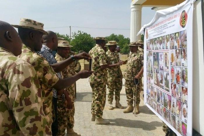 Soldiers look at the Nigerian army's latest list of most wanted Boko Haram members in Maiduguri, northeast Nigeria, on November 21, 2016