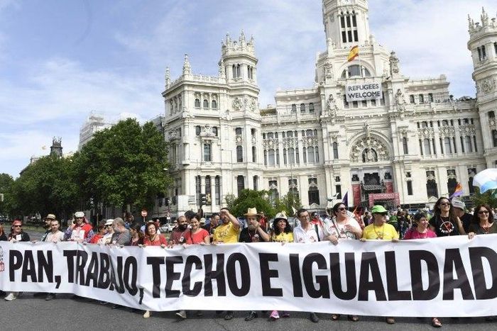 People hold a banner that reads "Bread, work, roof and equality" during a demonstration in Madrid on May 27, 2017 to denounce degraded working conditions