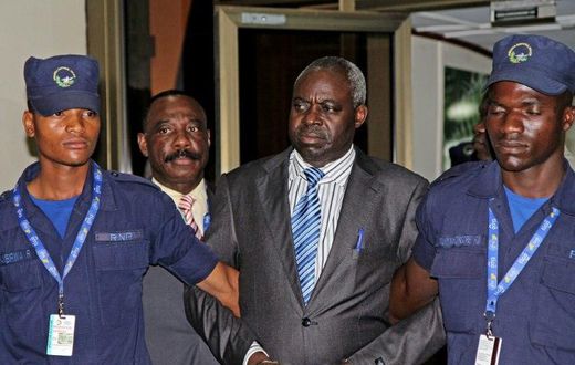 Former Hutu militia leader Bernard Munyagishari (C) is escorted by police upon his arrival at Kigali airport on July 24, 2013
