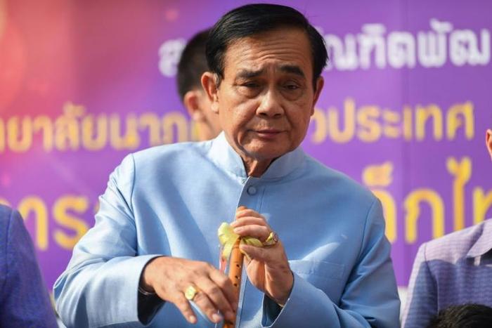 Thailand's Prime Minister Prayut Chan-O-Cha plays with a traditional flute as he arrives at the government house for a cabinet meeting on Tuesday, two days after the country's general election