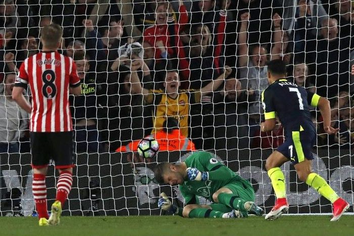 Arsenal's Alexis Sanchez (R) scores the opening goal past Southampton goalkeeper Fraser Forster on the way to a 2-0 Arsenal win