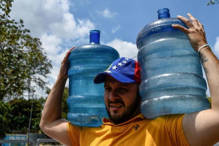 A man carries drums with water he collected from a stream at the Wuaraira Repano mountain, also called El Avila, in Caracas on March 13, 2019