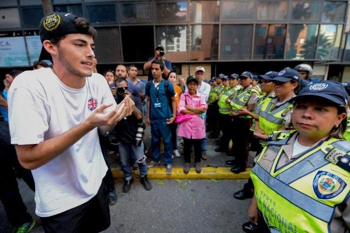 A student faces a line of police blocking a march in Caracas protesting the government of President Nicolas Maduro