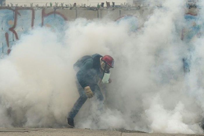 A demonstrator is swamped by tear gas during clashes with riot police during a protest against Venezuelan President Nicolas Maduro, in Caracas