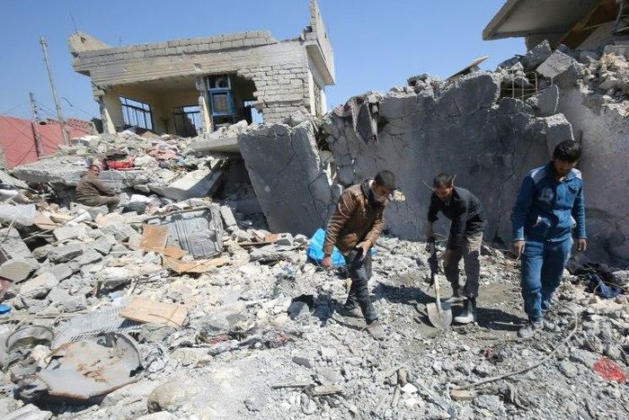 Iraqis clean up the rubble of destroyed buildings in the Mosul al-Jadida area following air strikes that reportedly killed civilians