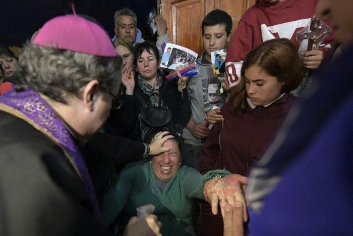 Bishop Manuel Acuna (L) performs a ritual at the 'El Buen Pastor' parish in Santos Lugares, on the outskirts of Buenos Aires