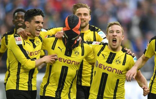 Dortmund's Pierre-Emerick Aubameyang (C) wears a mask as he celebrates with teammates after scoring against Schalke in Gelsenkirchen, western Germany, on April 1, 2017