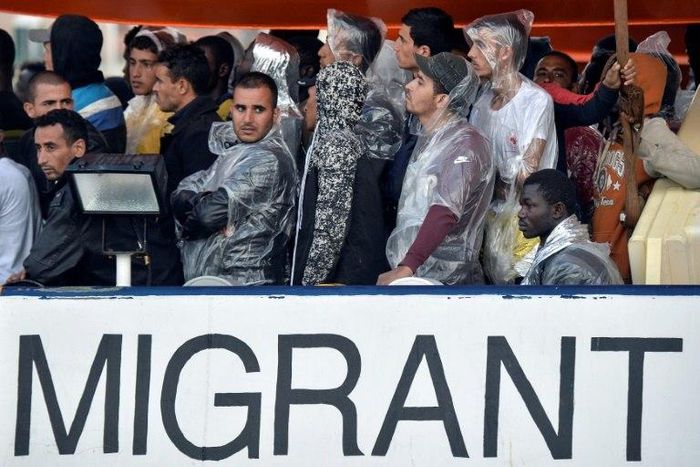Migrants and refugees look on as they are on board of the Topaz Responder, a rescue ship run by Maltese NGO MOAS during its arrival at the Brindisi's harbour on October 27, 2016