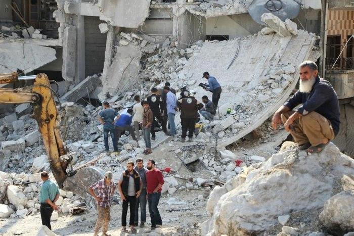 Volunteers search for victims amid the rubble of destroyed buildings on October 24, 2016, following air strikes in the rebel-held town of Kafar Takharim, in Idlib province