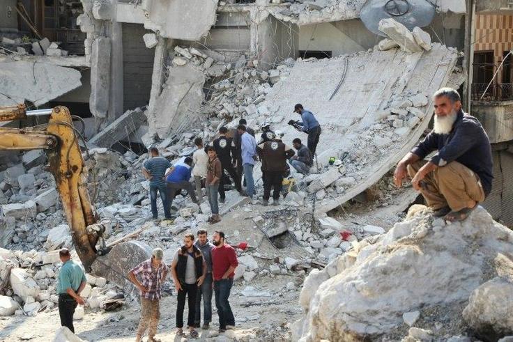 Volunteers search for victims amid the rubble of destroyed buildings on October 24, 2016, following air strikes in the rebel-held town of Kafar Takharim, in Idlib province