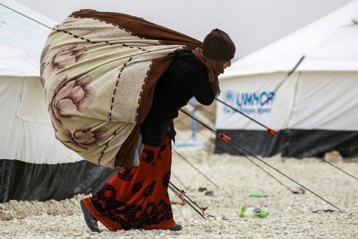 A displaced Syrian woman fleeing from Deir Ezzor, a city besieged by IS group fighters, carries blankets through a refugee camp in al-Hol, near the Iraqi border in northeastern Syria's Hasakeh province, on February 1, 2017