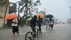 Haitian people travel in a flooded street through the rain, during a tropical storm in the commune of Les Cayes, Haiti, on October 21, 2016